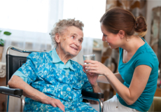 A caregiver giving an elderly a glass of water