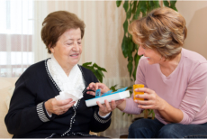 A caregiver giving an elderly her medications