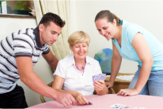 Caregivers accompanying an elderly in playing cards